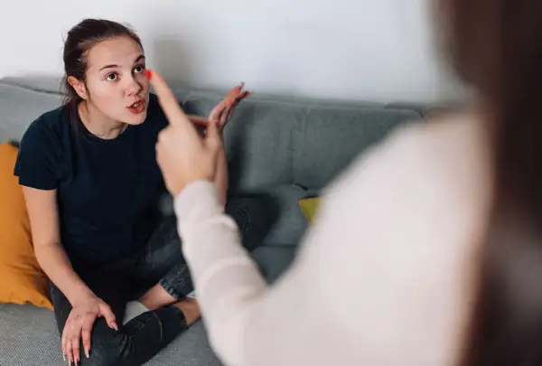 Junge Frau zeigt wütend mit dem Finger auf ihre Mutter. Der Sohn ist aggressiv gegen die Mutter.